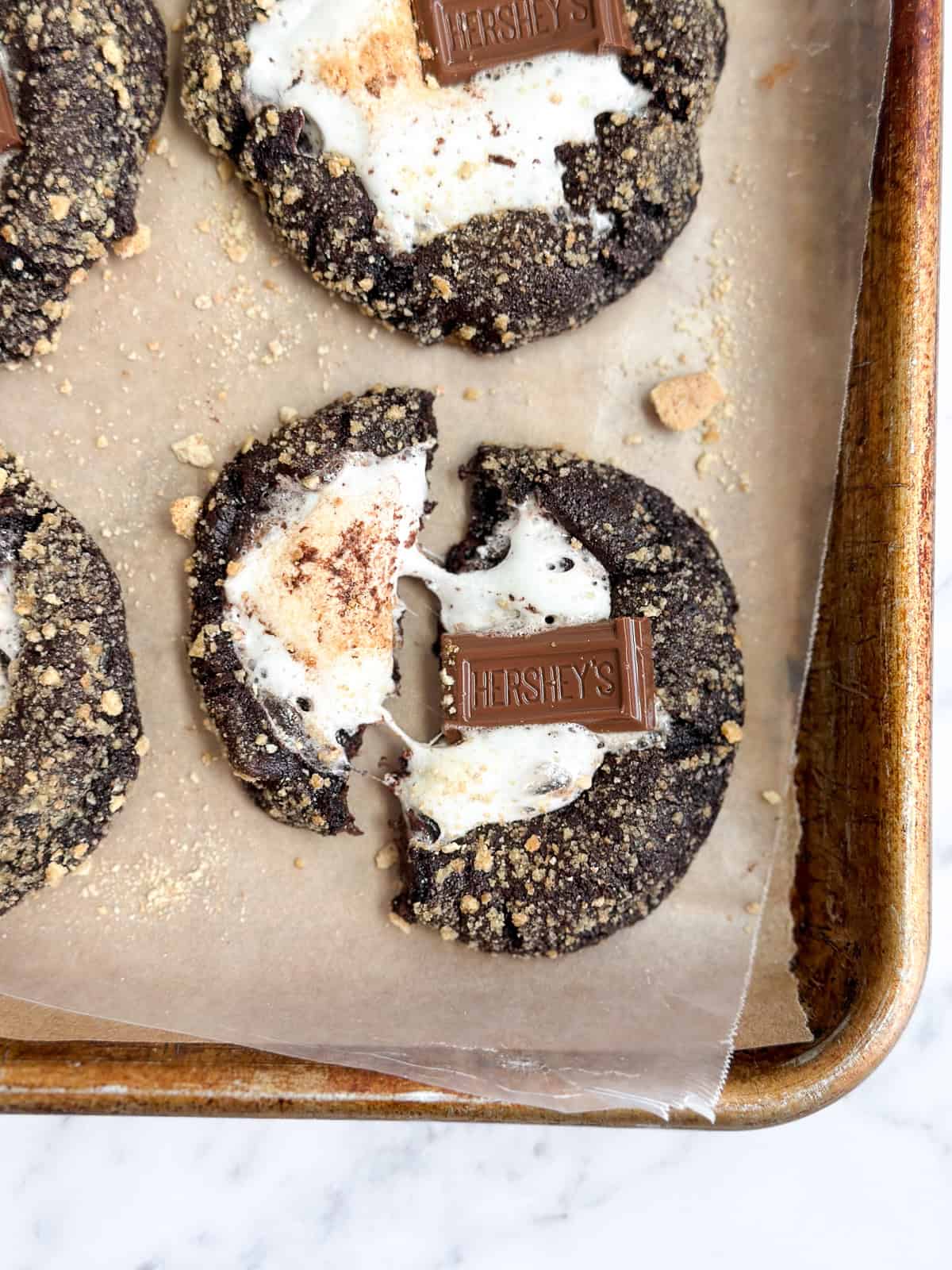 quelques biscuits s'more au double chocolat avec un cassé, mais la guimauve encore attachée.