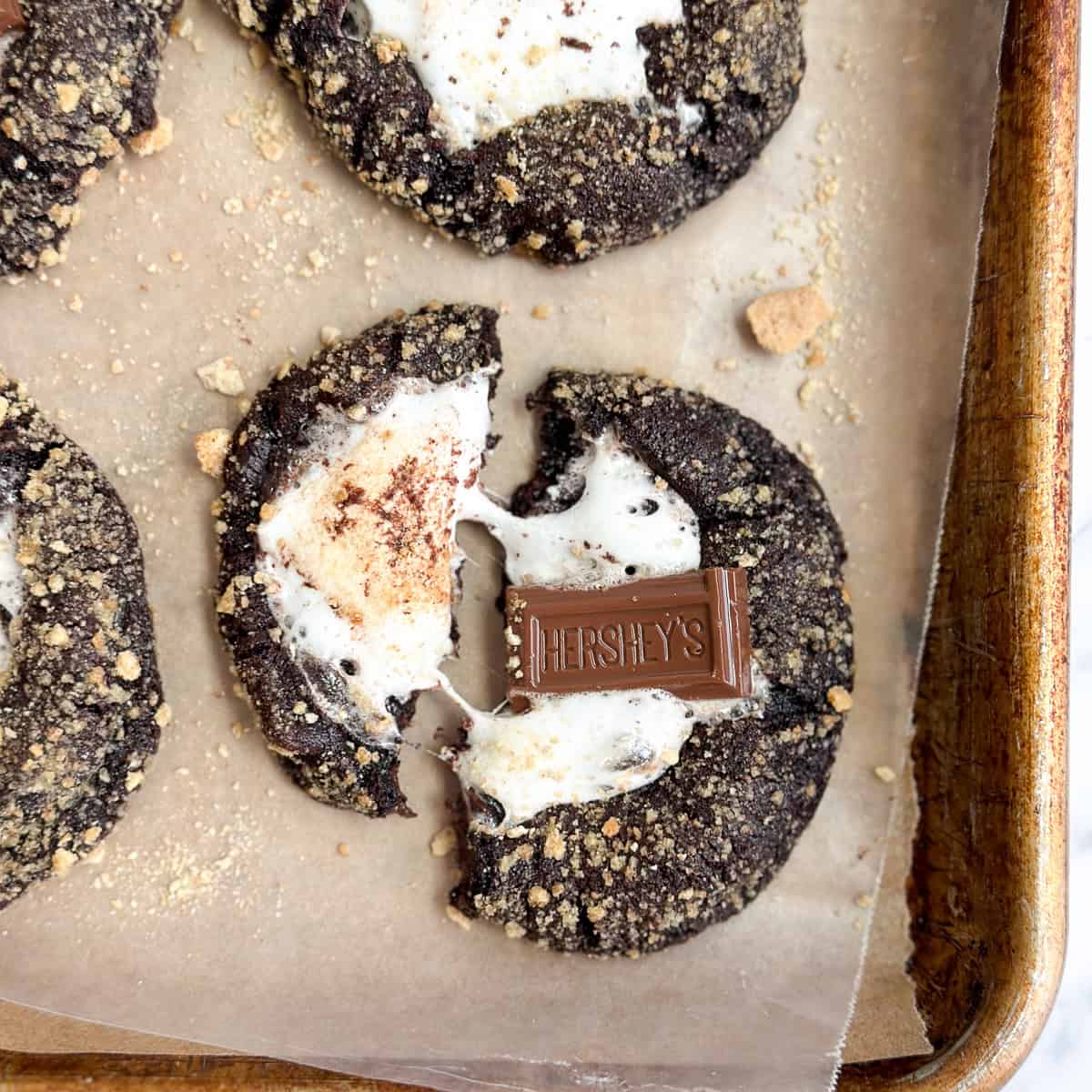 a few double chocolate s'more cookies with one broken, but marshmallow still attached.