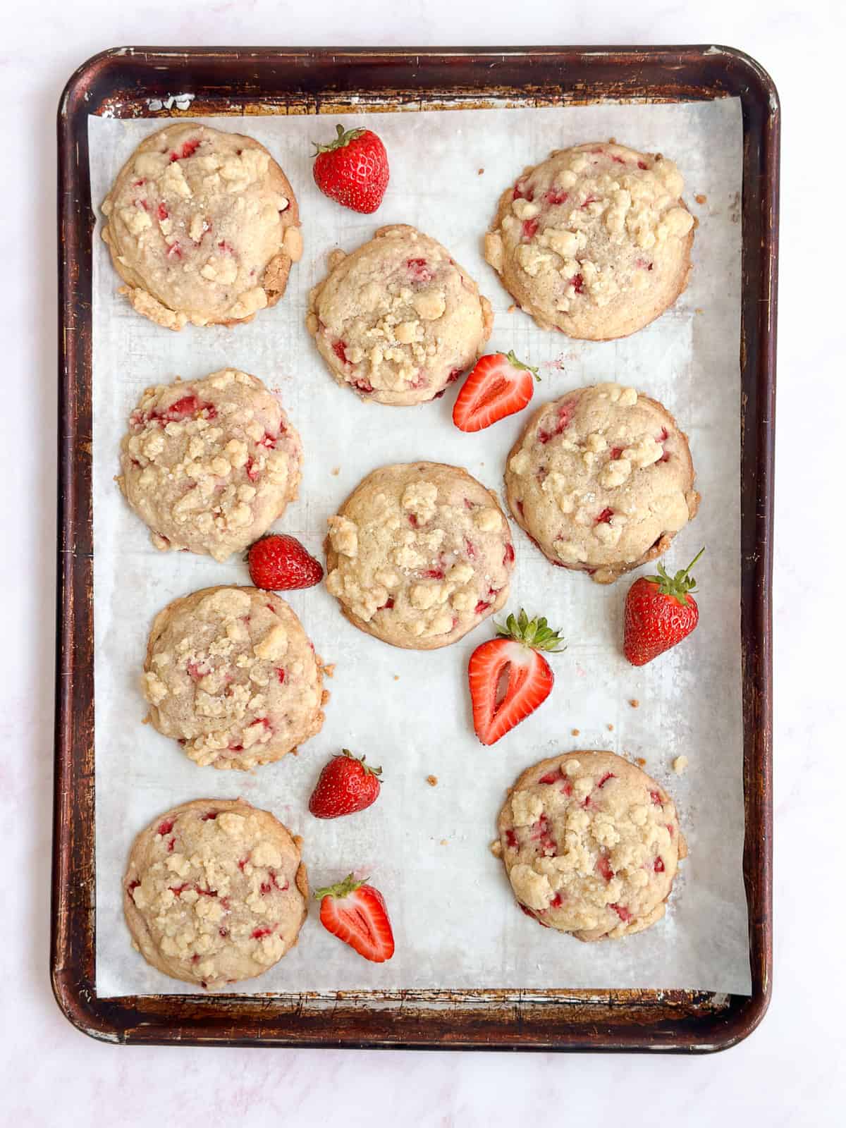 all the strawberry crumble cookies on a cookie sheet with some fresh diced strawberries.
