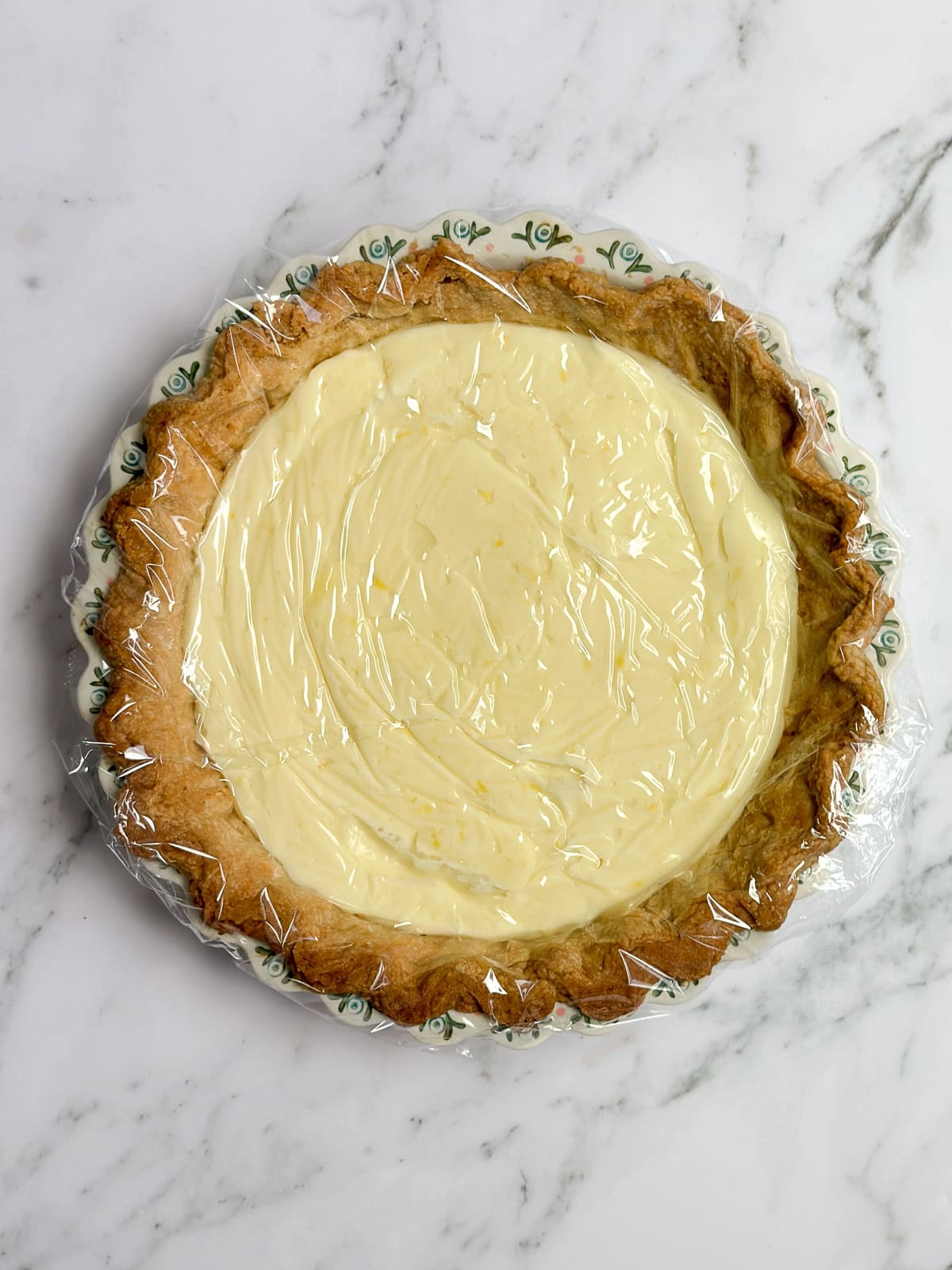 pie filling added to crust and then topped with saran wrap to chill.