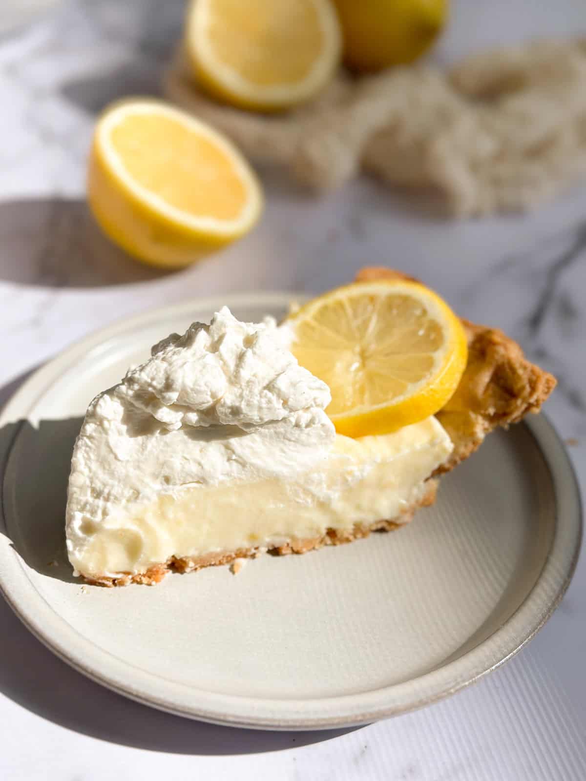 a single slice of lemon sour cream pie on a plate topped with a lemon slice.