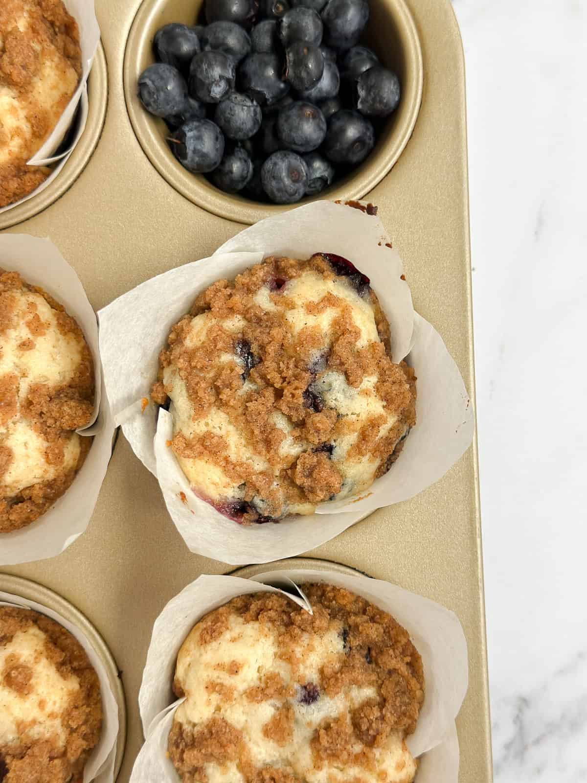 blueberry coffee cake muffins in the m muffin tin after baking.