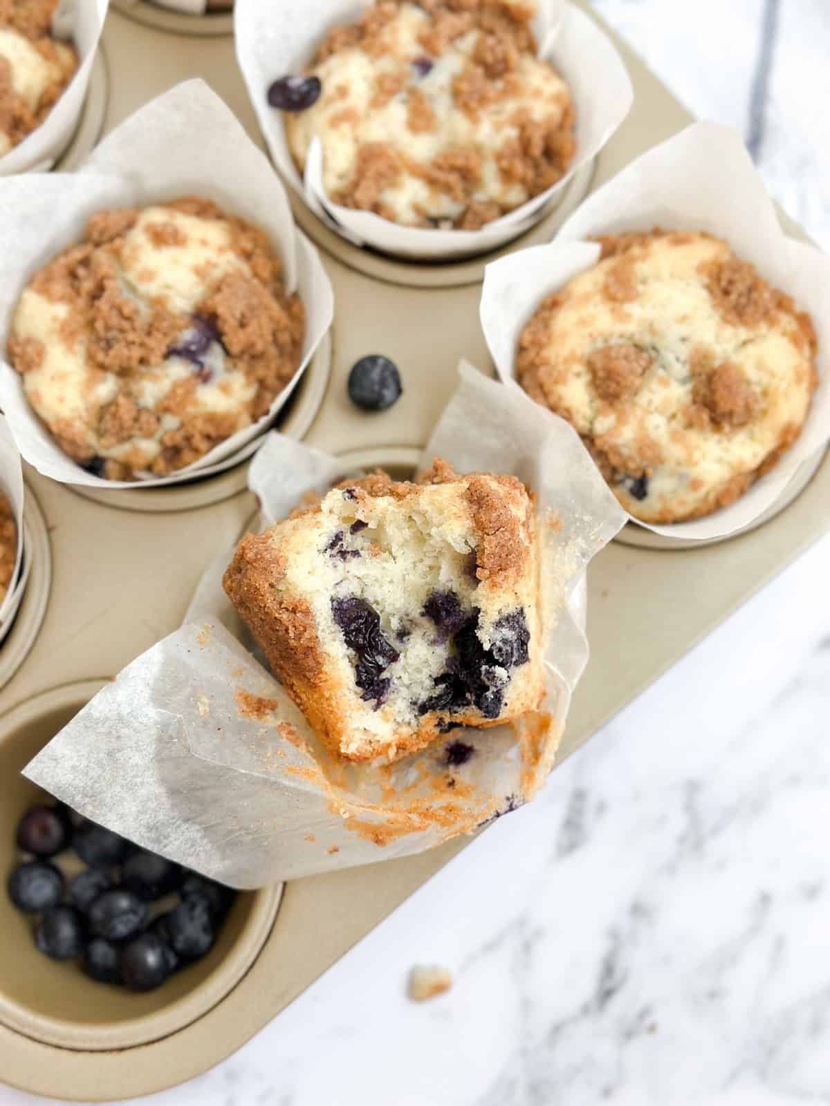 a bite missing from a blueberry coffee cake muffin.