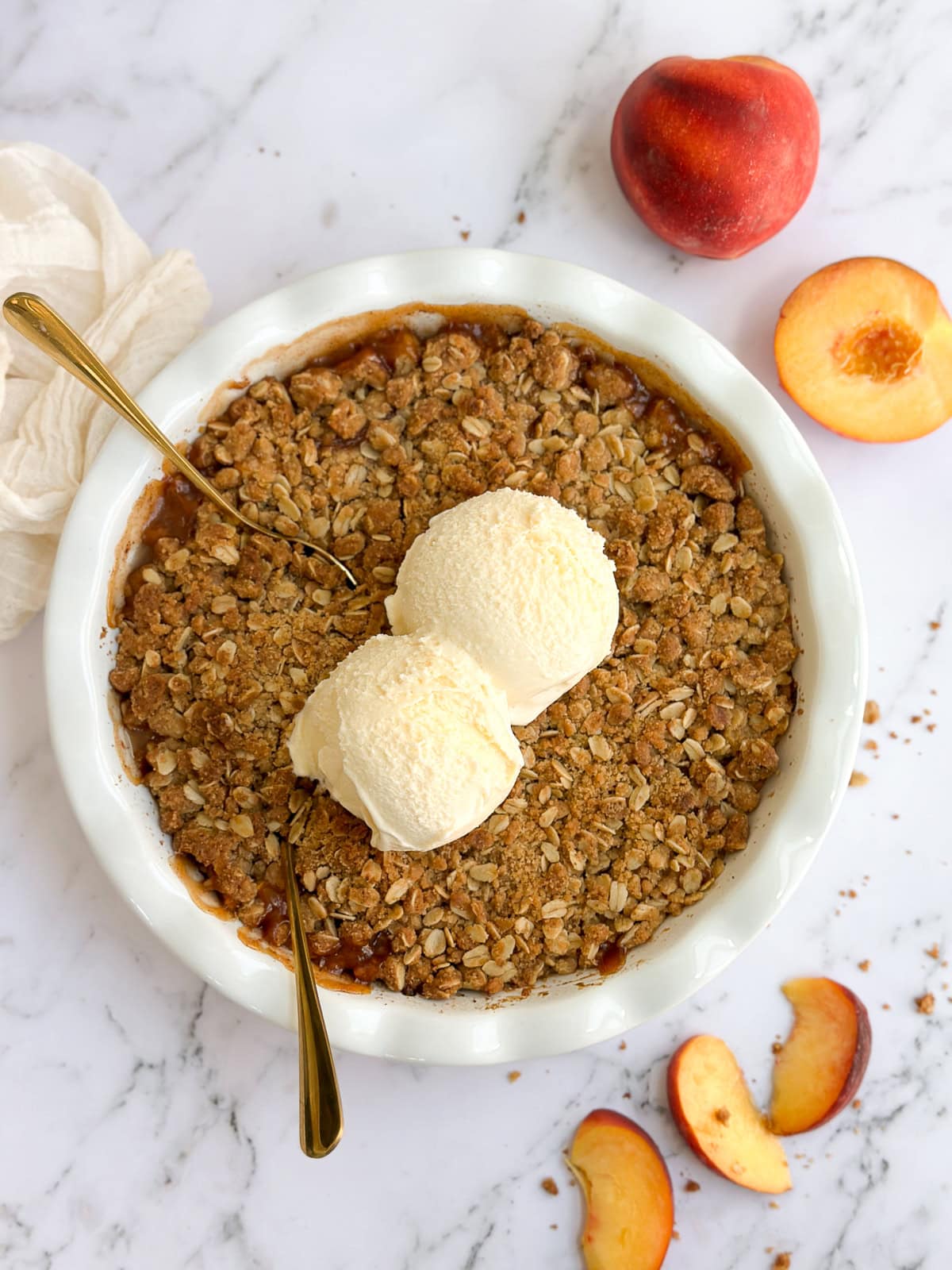 the whole brown butter peach crisp topped with vanilla ice cream.