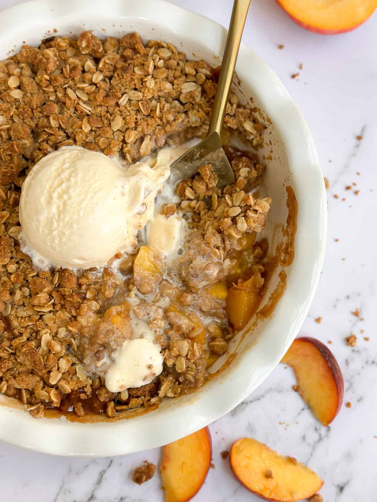 a large spoon dished into the whole brown butter peach crisp.