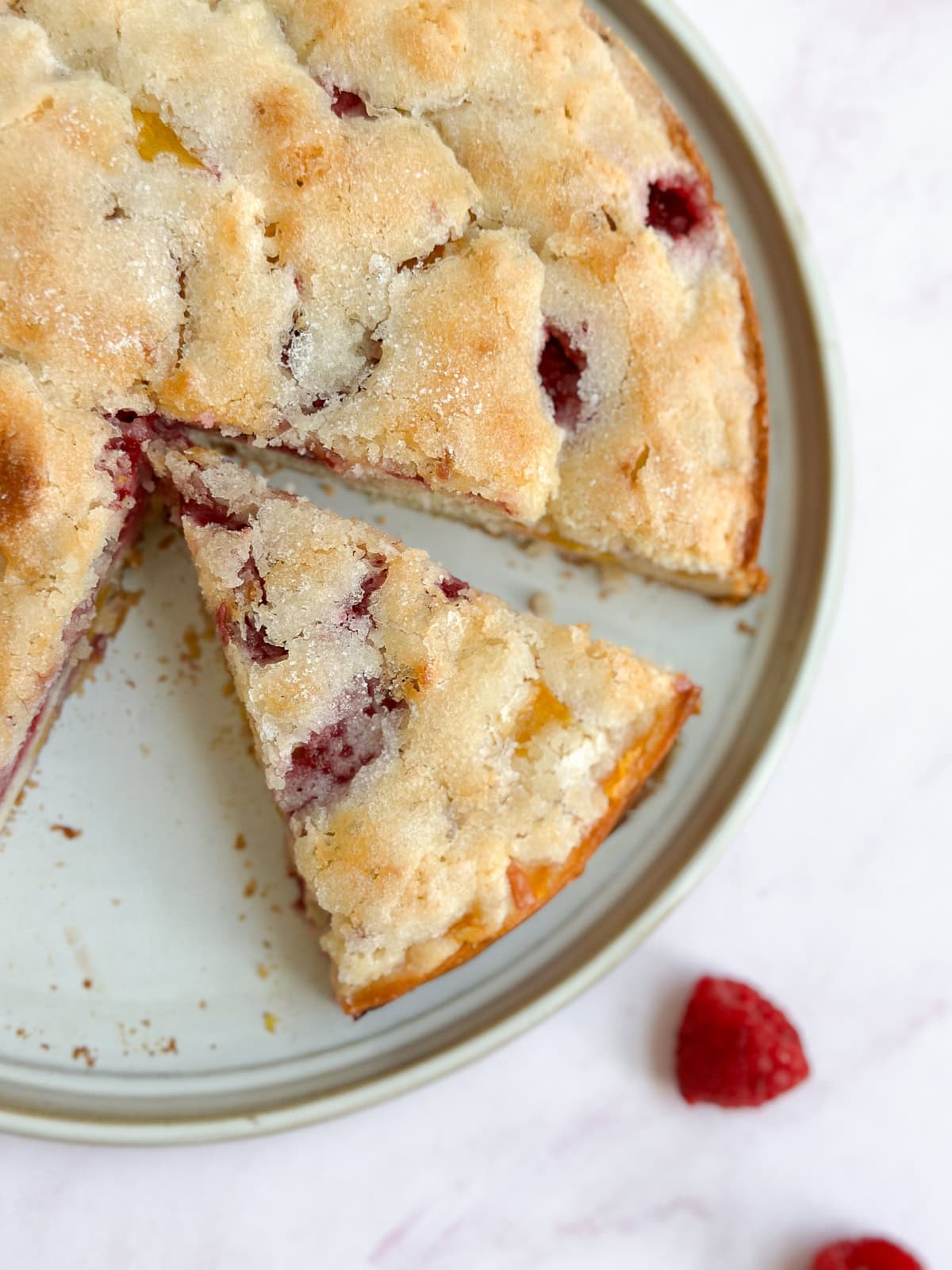 Une part de gâteau à la framboise et à la pêche séparée du reste du gâteau.