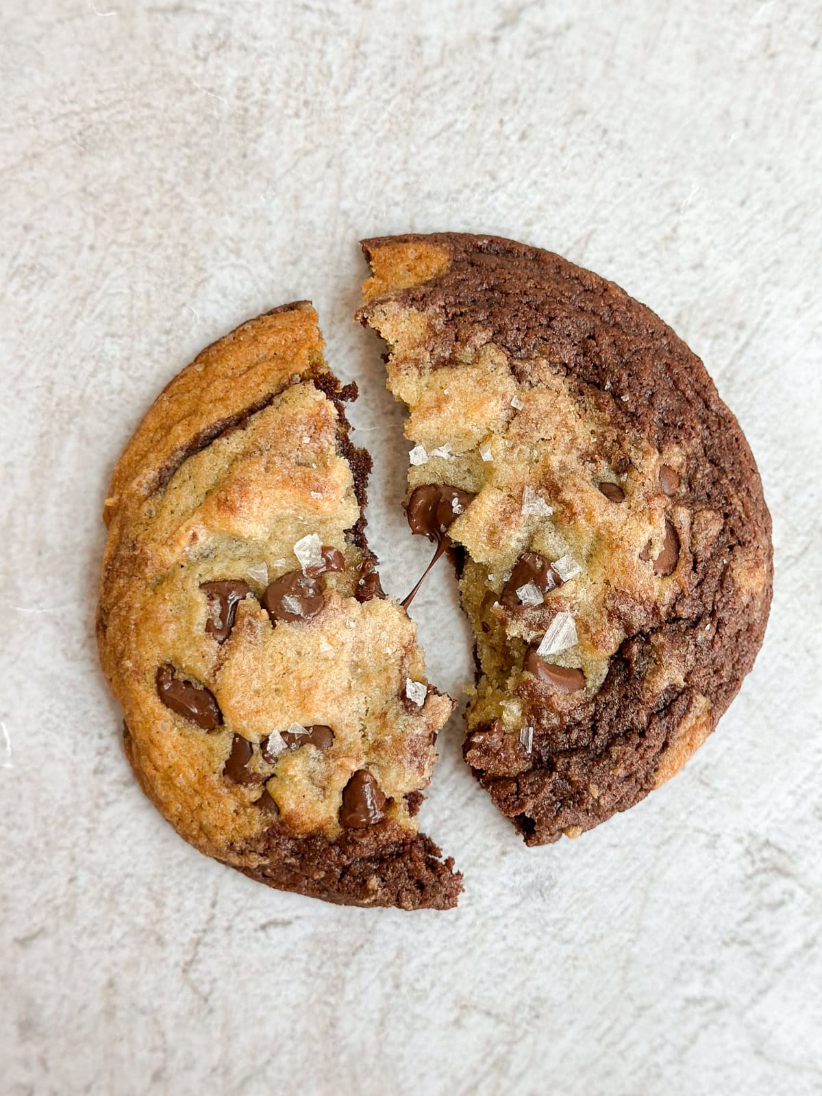 un cookie brookie coupé en deux avec du chocolat fondant entre les morceaux