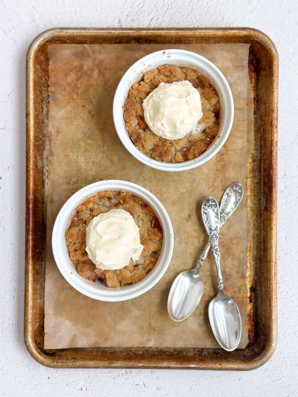 deux mini cobblers aux pêches sur une plaque de cuisson avec deux cuillères.