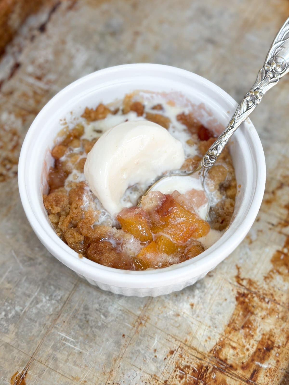 glace fondue sur le cobbler aux pêches avec une cuillère de dessert.