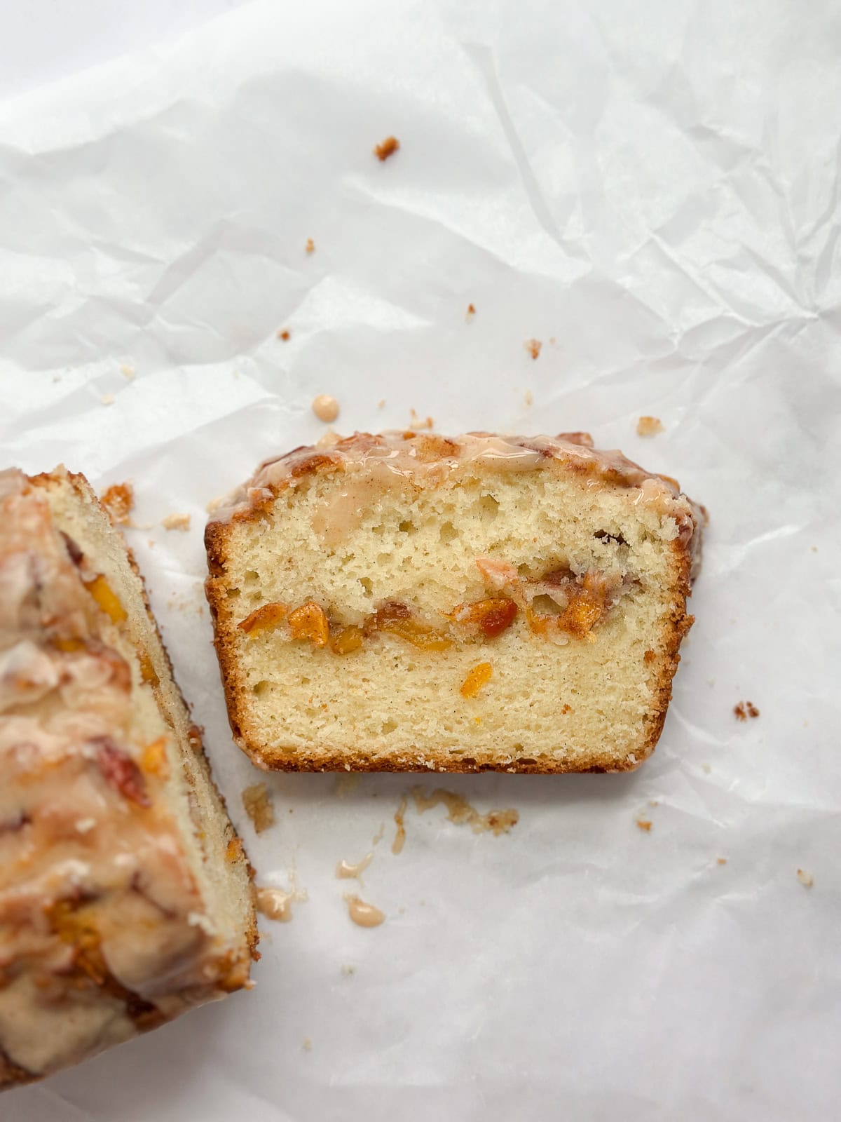 Une tranche de gâteau de pain aux pêches avec le gâteau entier à côté.
