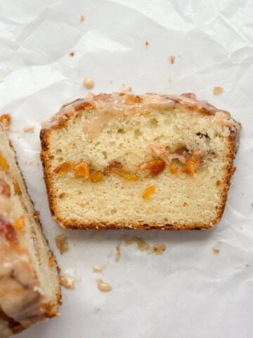 a slice of peach loaf cake with the whole loaf to the side of it.
