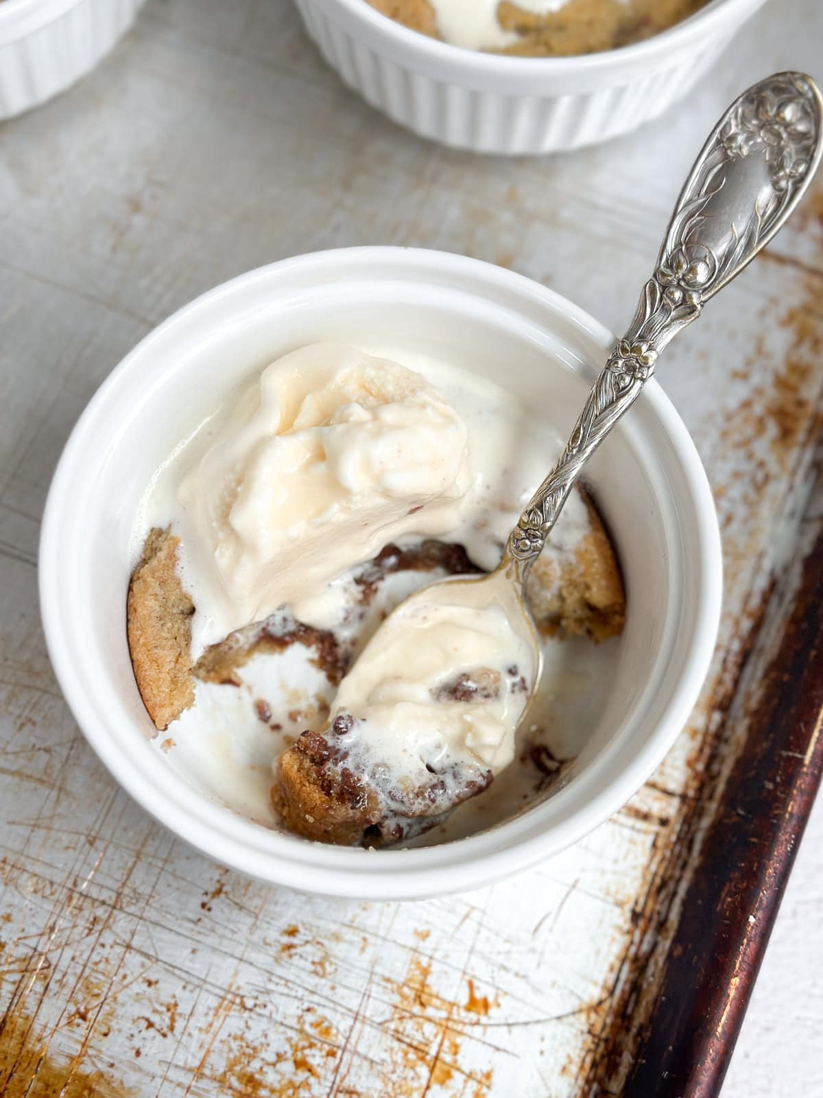 a half eaten mini chocolate chip cookie sundae with melty ice cream and chocolate in a spoon.