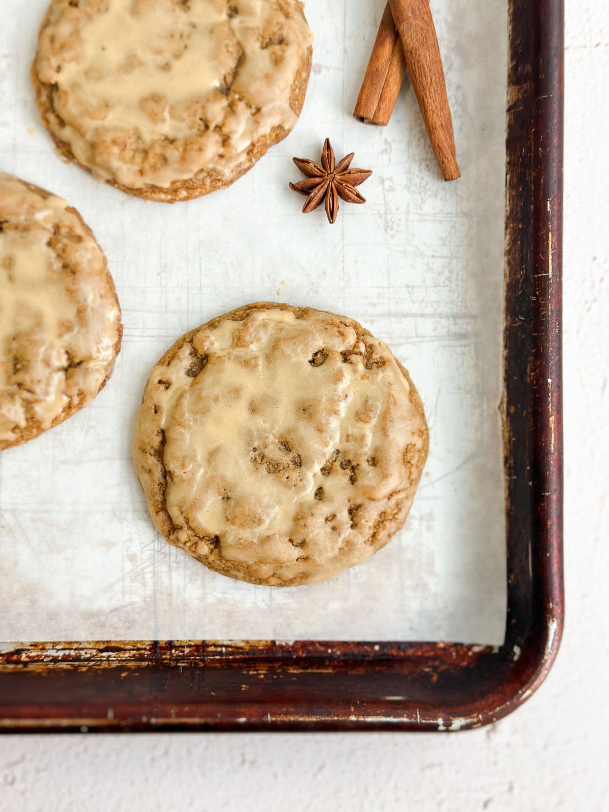 Quelques cookies au latte à la citrouille sur une plaque à pâtisserie avec des bâtons de cannelle à côté.