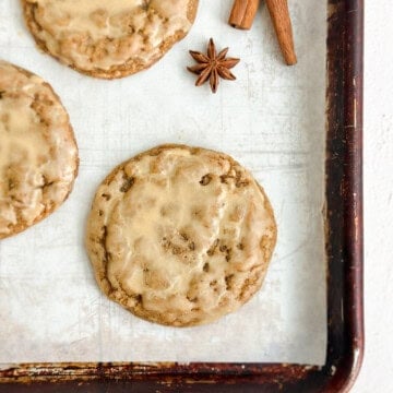 a few pumpkin spice latte cookies on a cookie sheet with some cinnamon sticks next to them.