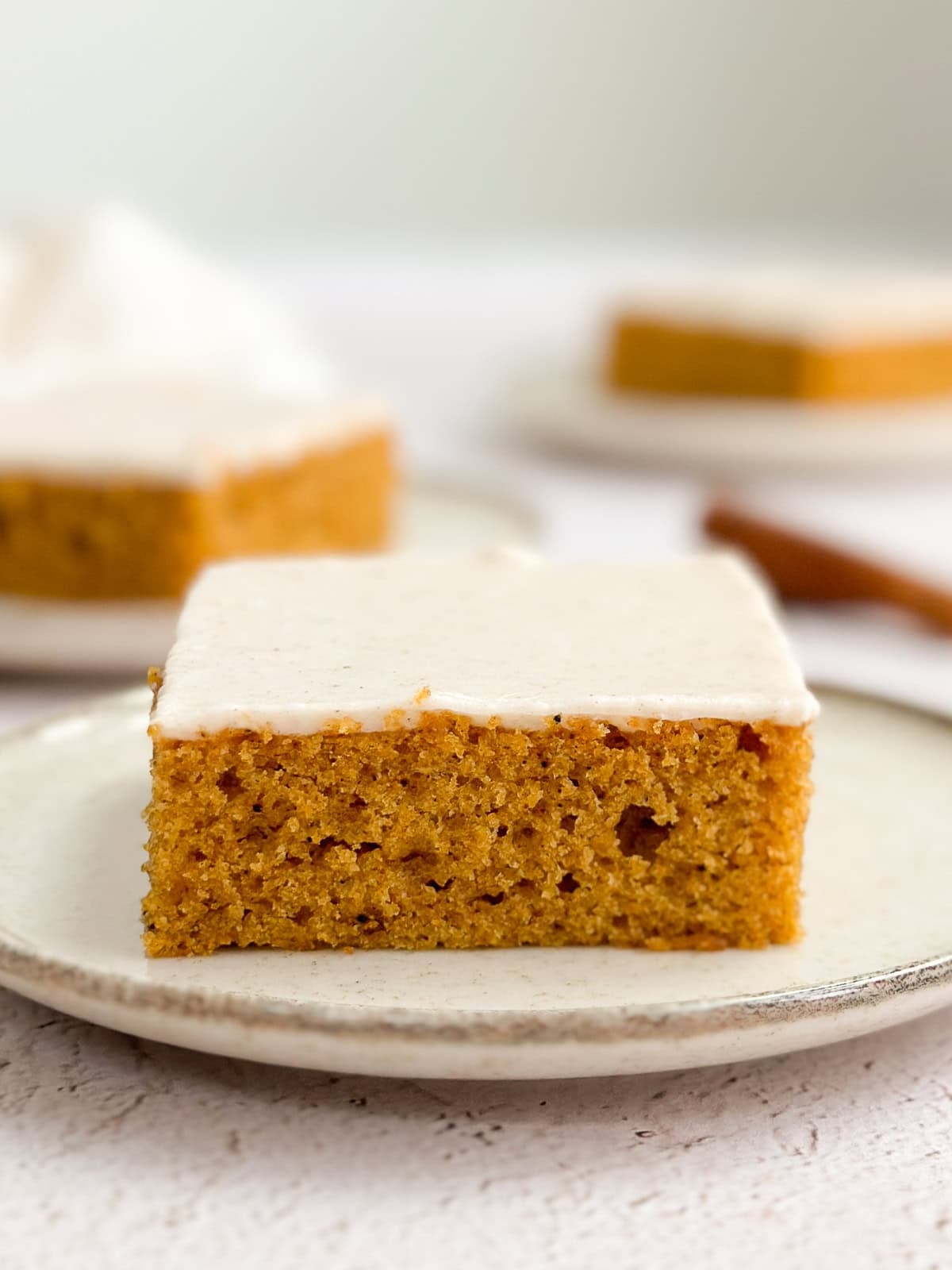 a side view of a pumpkin bar with cinnamon cream cheese frosting so you can see the texture and layers.