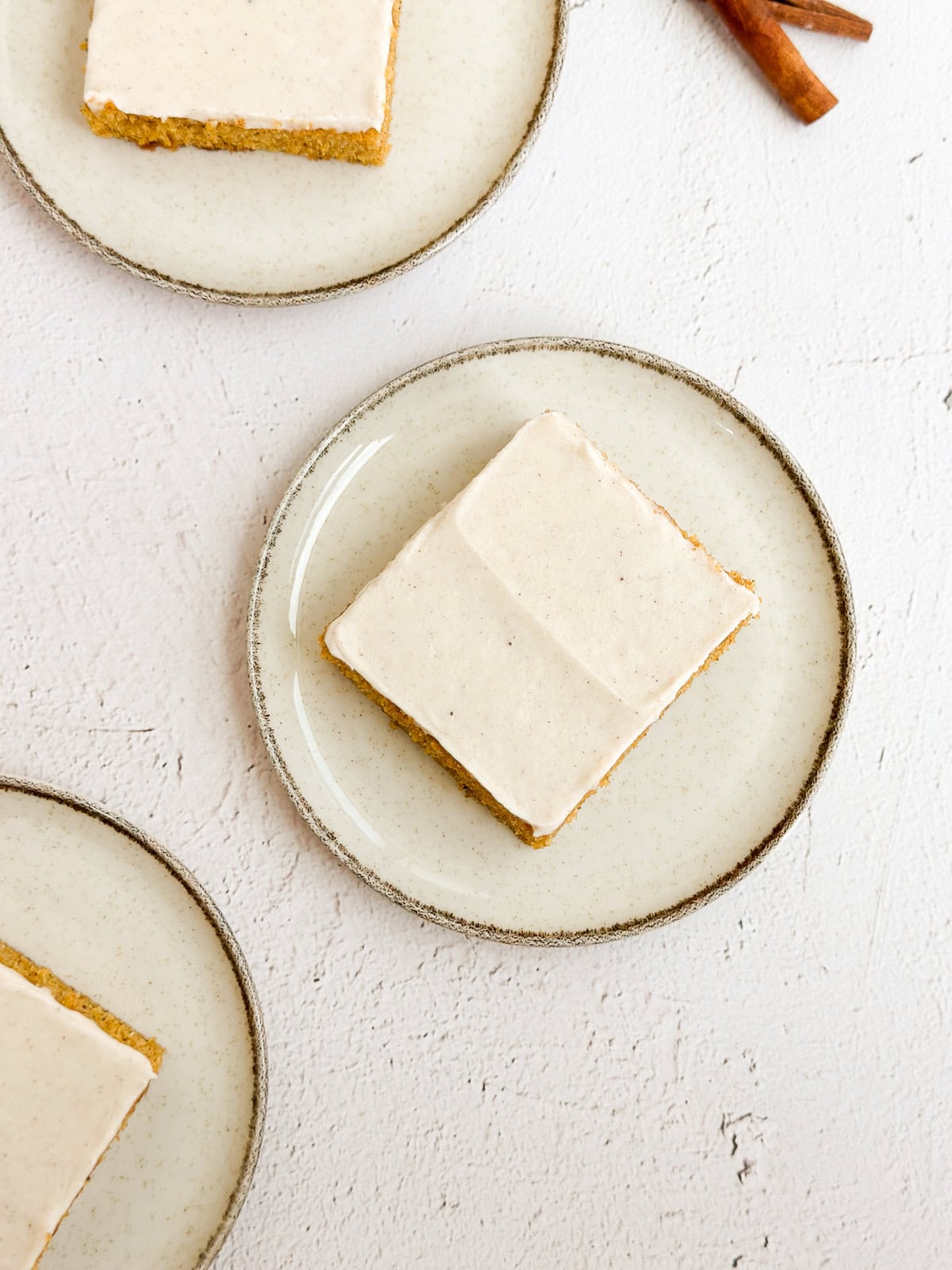Quelques barres de citrouille sur des assiettes avec des bâtons de cannelle à côté.