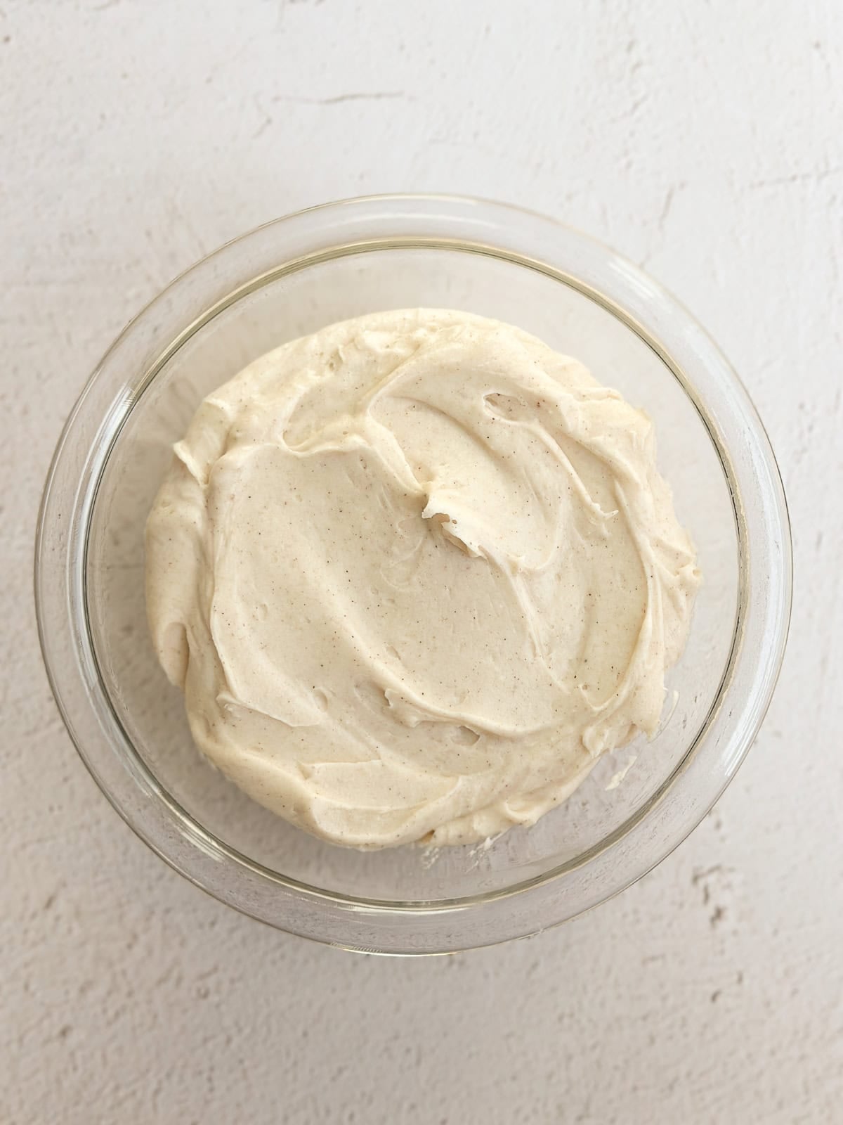 the cinnamon cream cheese frosting in a bowl after being mixed together.