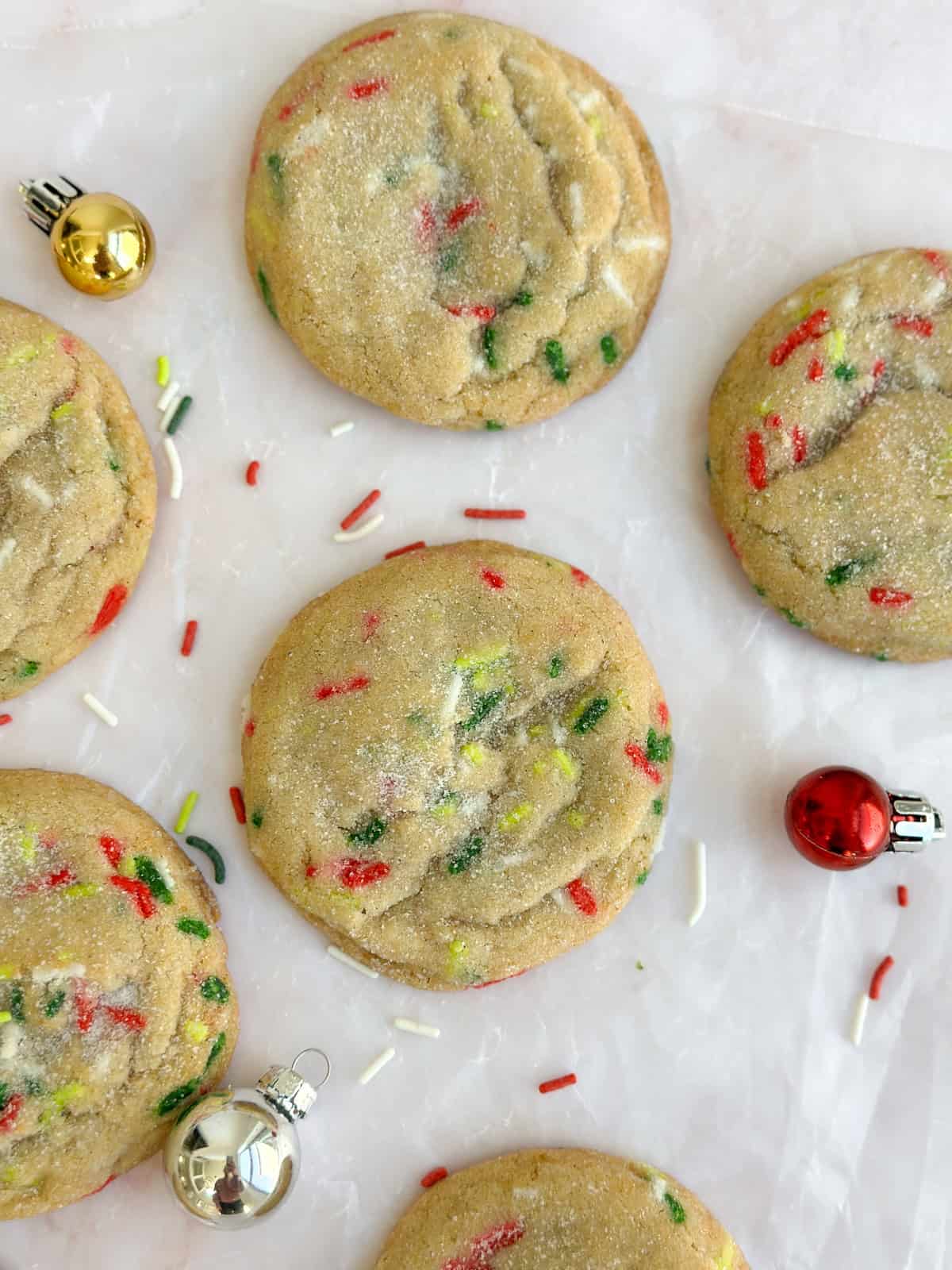 a bunch of christmas sprinkle sugar cookies with extra sprinkles all around.