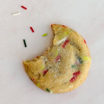 a christmas sprinkle sugar cookie with a bite missing.