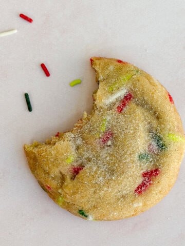 a christmas sprinkle sugar cookie with a bite missing.