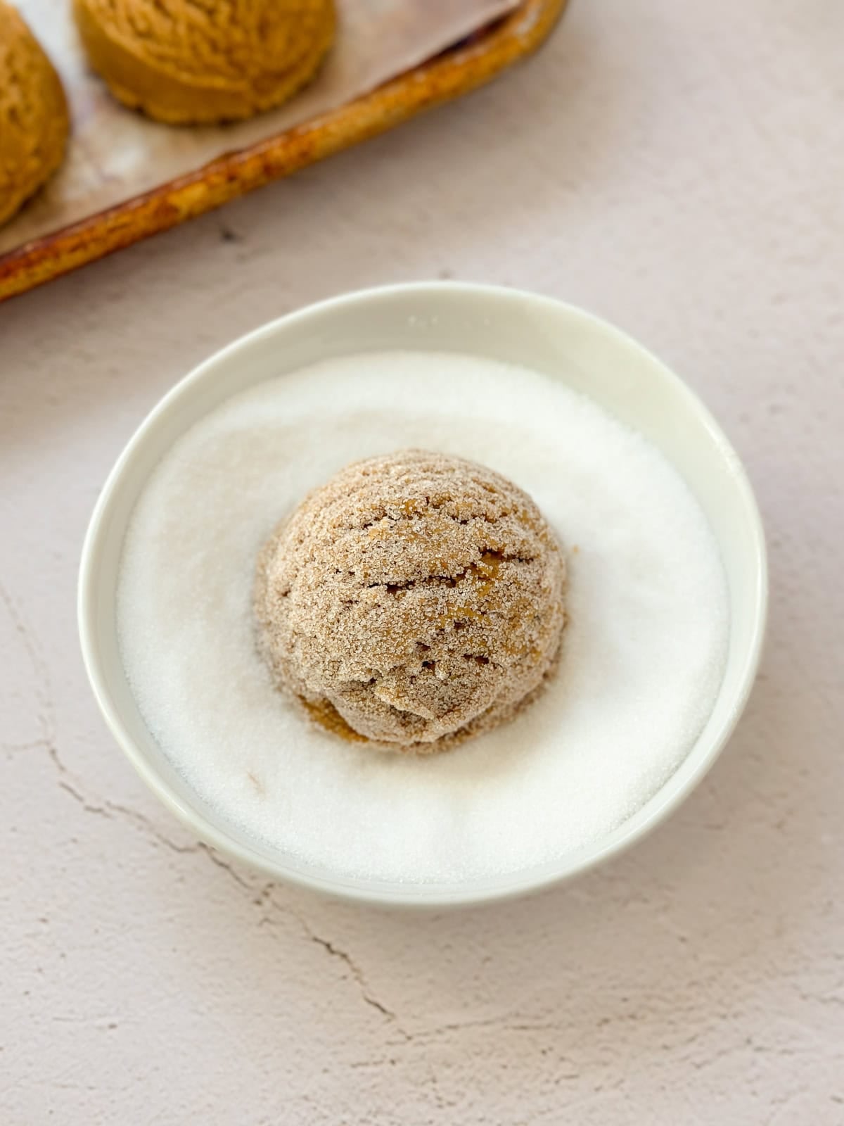 a cookie ball being rolled in the sugar.
