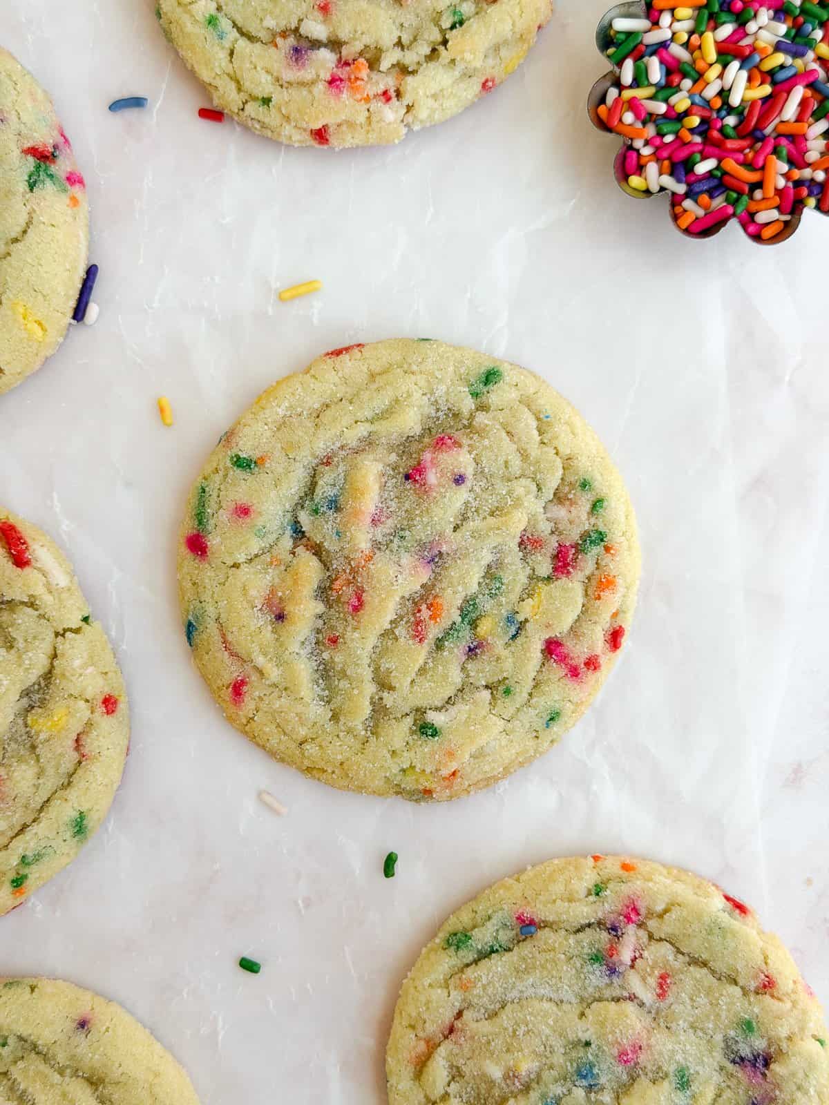 a close up of a sprinkle sugar cookie with sprinkles around it.