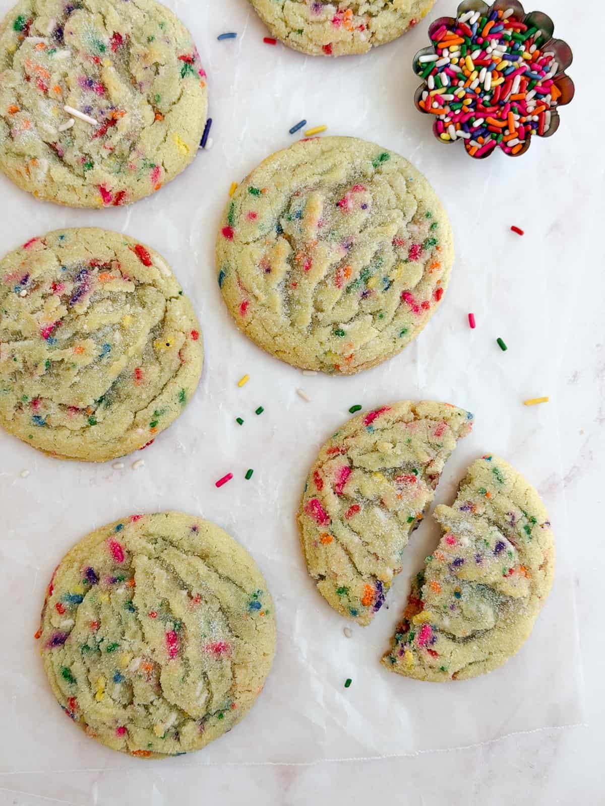 a few sprinkle sugar cookies together and one broken in half.