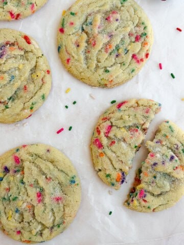 a few sprinkle sugar cookies together and one broken in half.