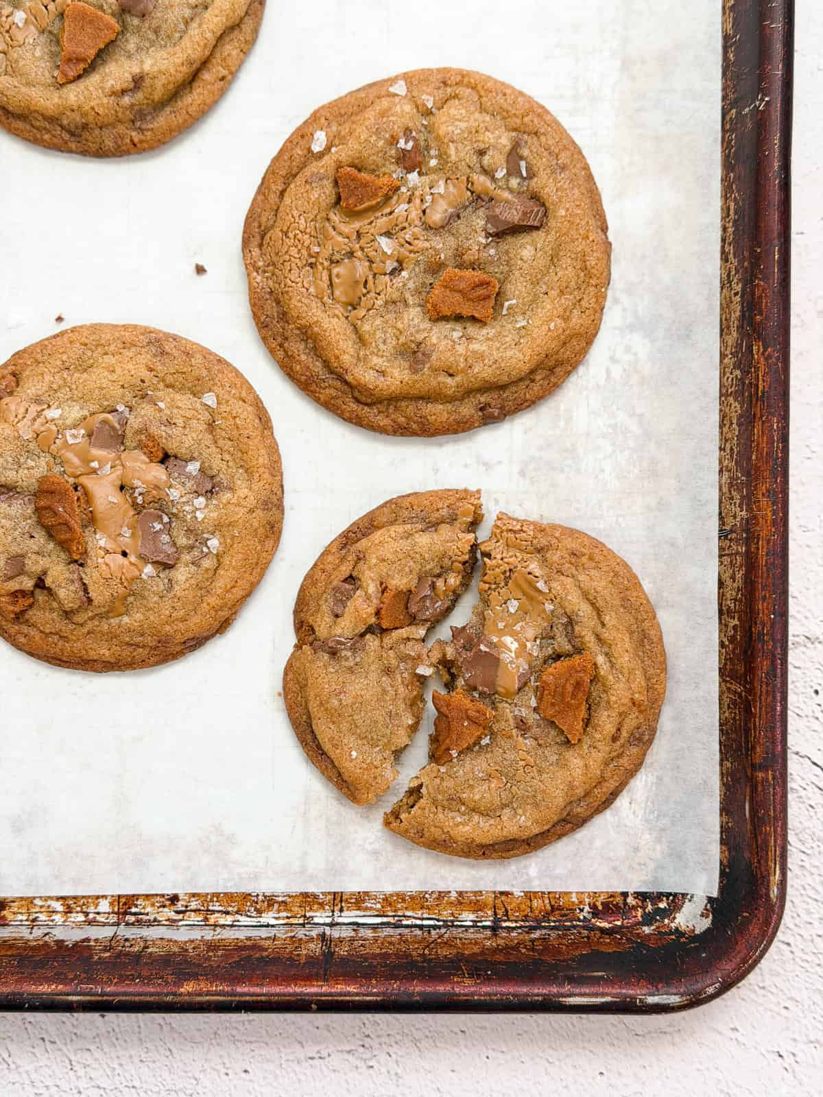 a broken biscoff chocolate chip cookie with others around it.