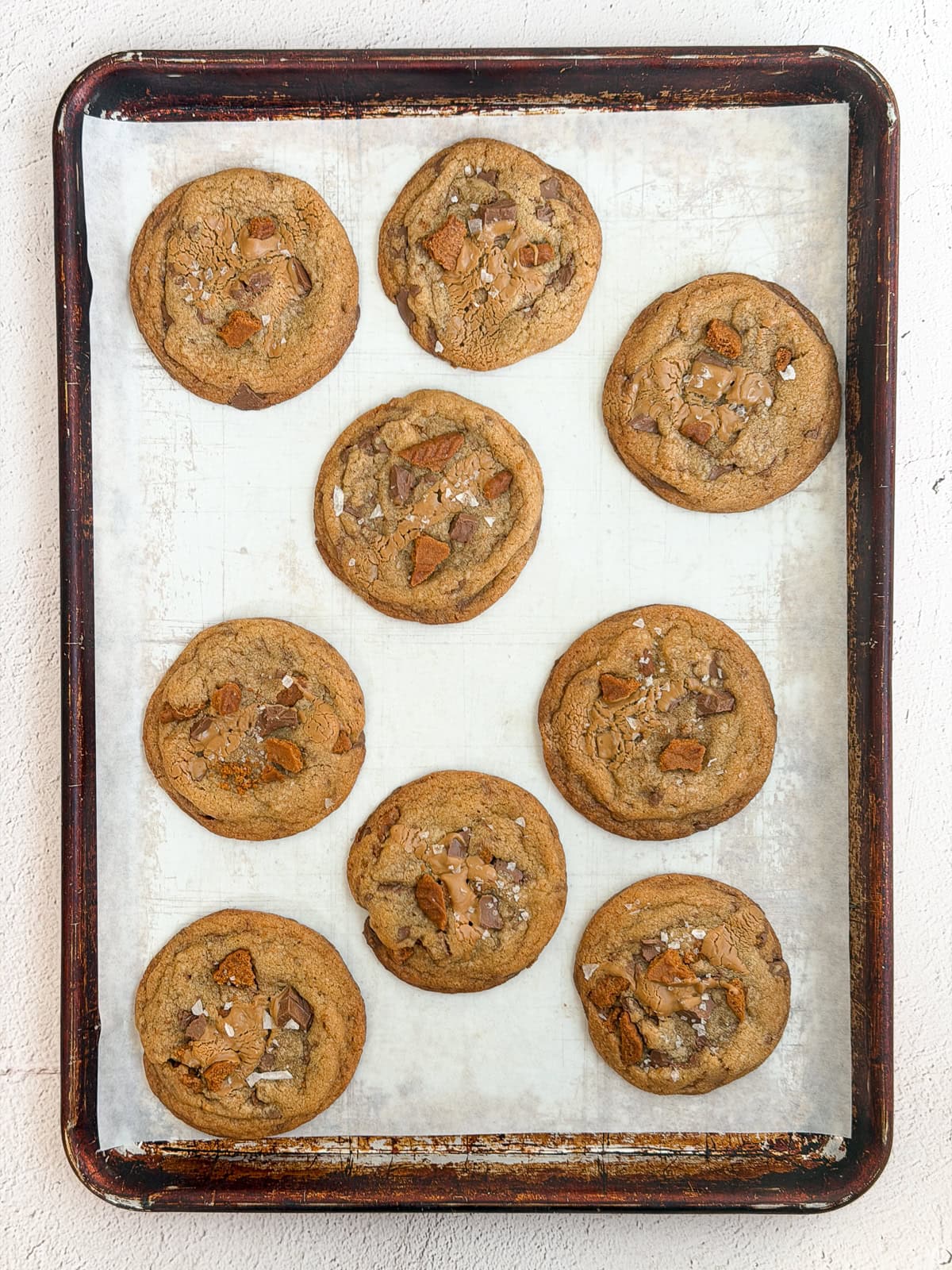 all the biscoff chocolate chip cookies scattered on a cookie sheet after baking.