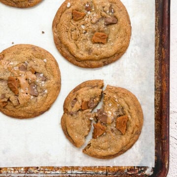 a broken biscoff chocolate chip cookie with others around it.