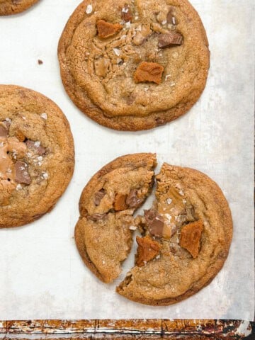 a broken biscoff chocolate chip cookie with others around it.