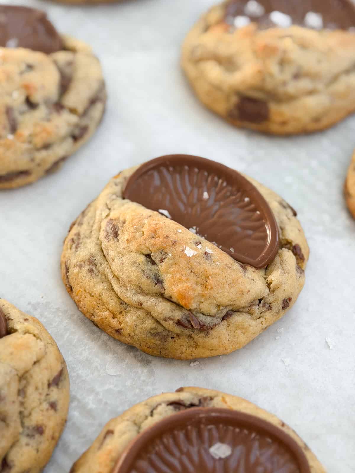 Gros plan d'un cookie au chocolat et à l'orange surmonté d'une tranche d'orange.