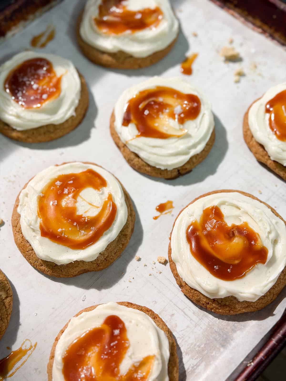 a side view of a bunch of salted caramel cheesecake cookies on a baking sheet.