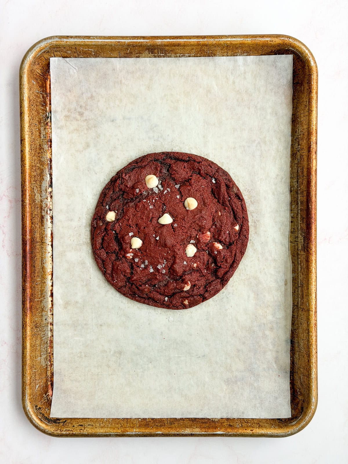 a single serve red velvet cookie on a baking sheet after baking.