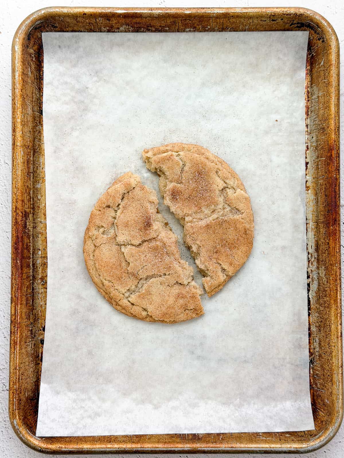 a single serve snickerdoodle cookie broken in half.