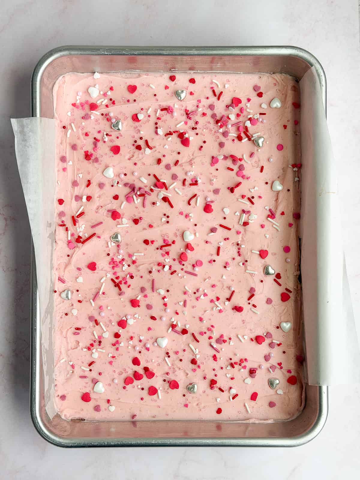 chewy sugar cookie bars after frosting and topping with sprinkles.