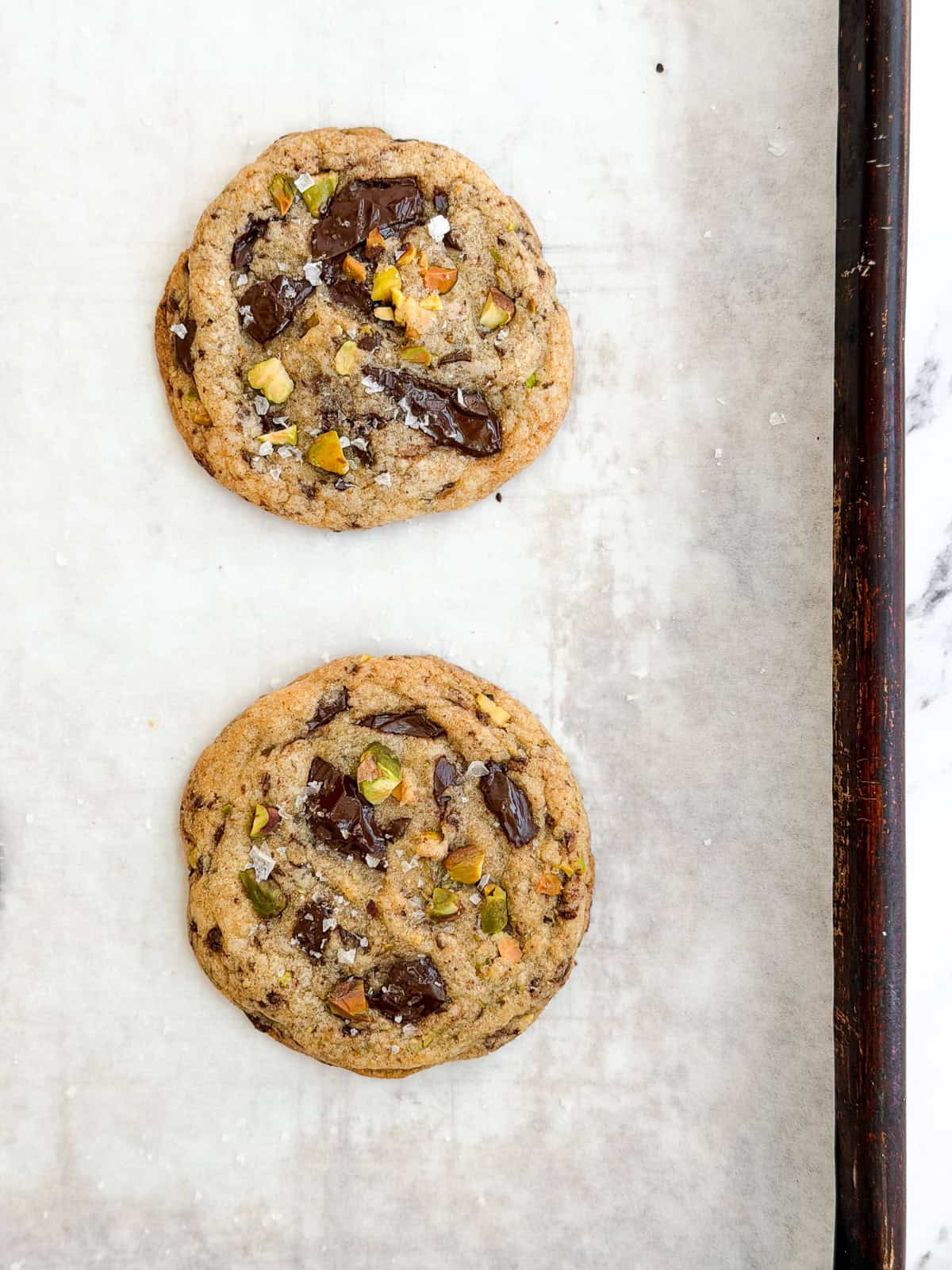 freshly baked pistachio chocolate chip cookies on a baking sheet.