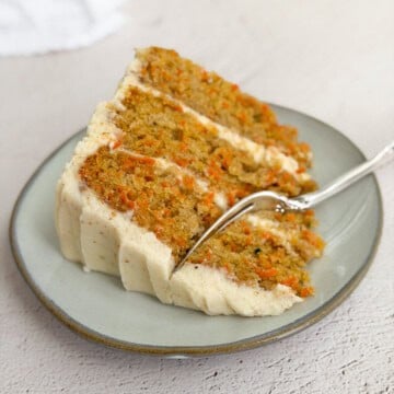 a slice of the carrot cake with brown butter cream cheese frosting on a plate.
