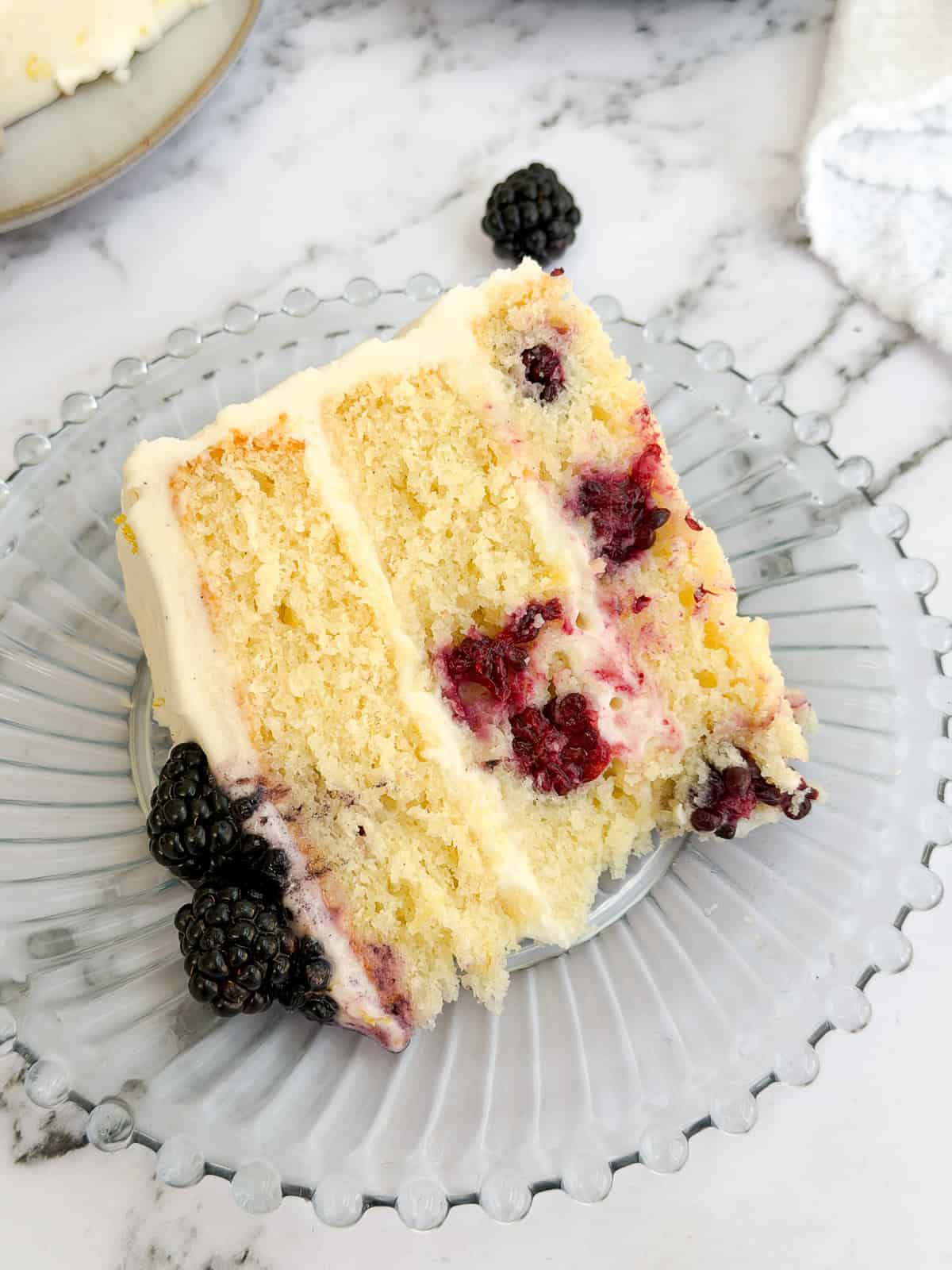 a close up of a single slice of lemon blackberry layer cake.
