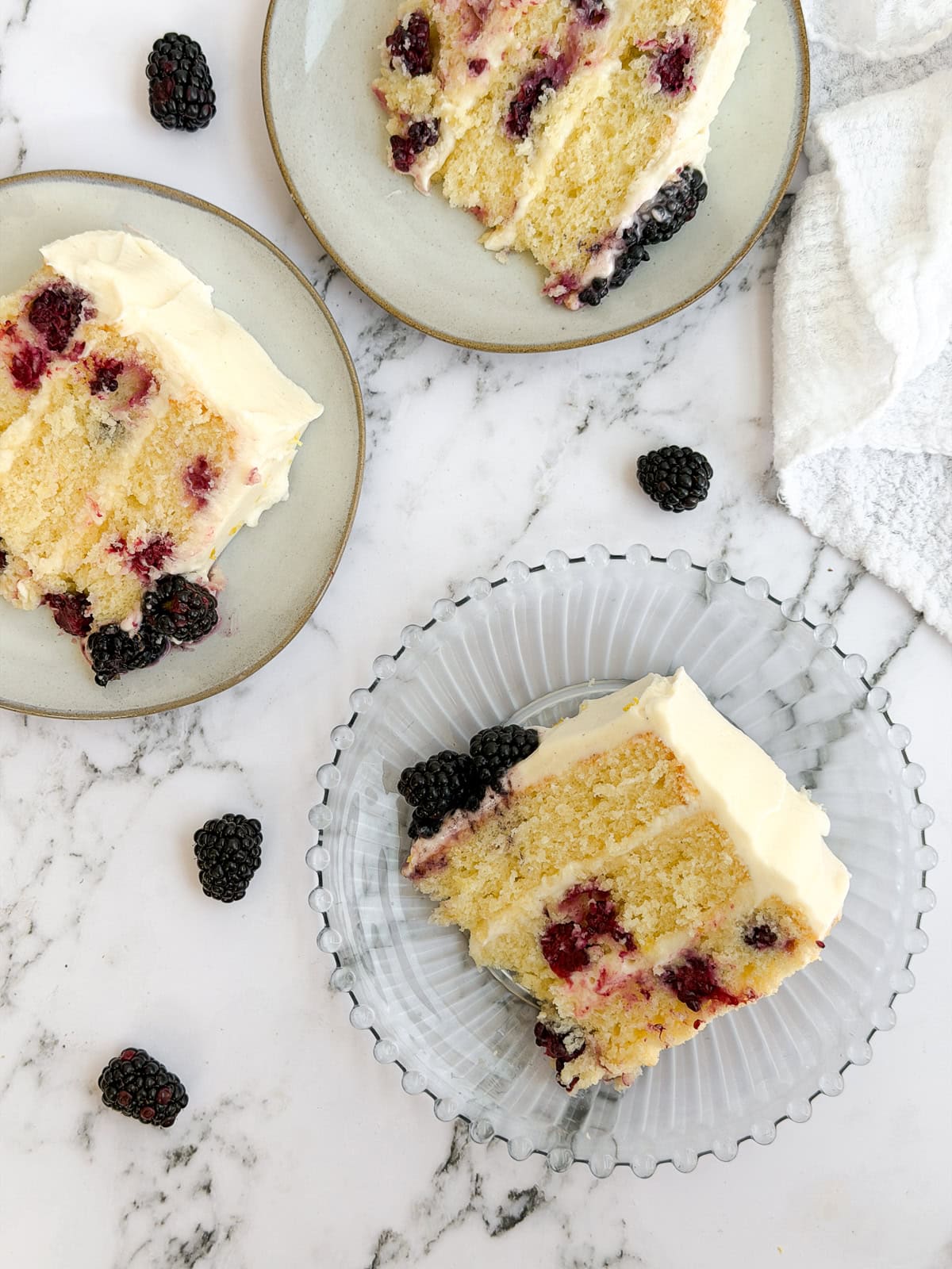 3 slices of lemon blackberry layer cake on plates.