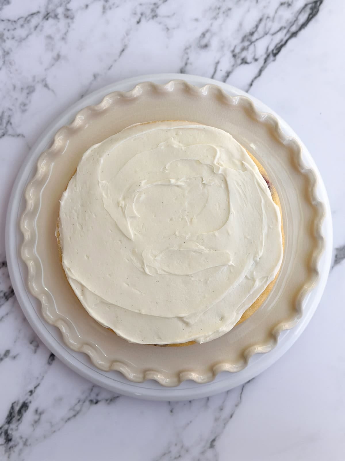 frosting being added in between layers of the cake.