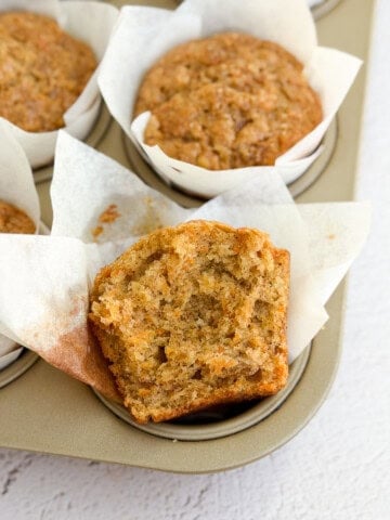 a close up of a banana carrot muffin with a bite missing to see the inside texture.
