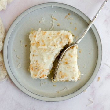 a fork cutting through a slice of coconut texas sheet cake.