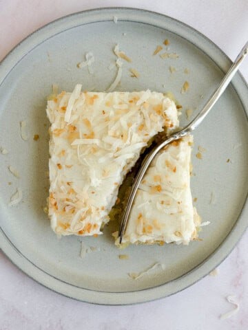 a fork cutting through a slice of coconut texas sheet cake.
