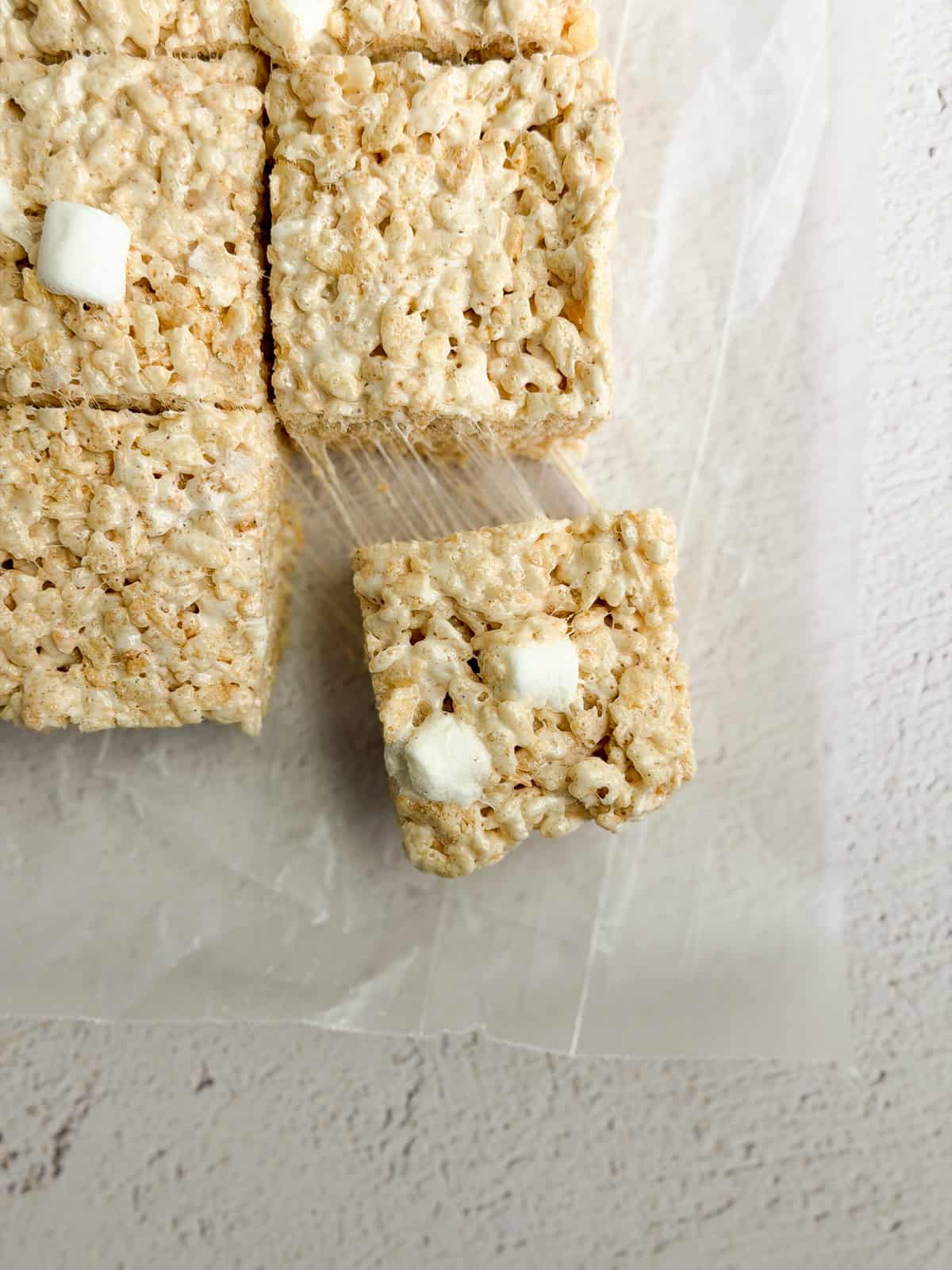 a close up of brown butter rice krispie treats with a marshmallow being pulled and stretched.