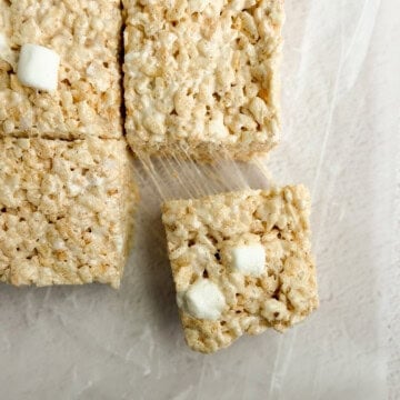 a close up of brown butter rice krispie treats with a marshmallow being pulled and stretched.