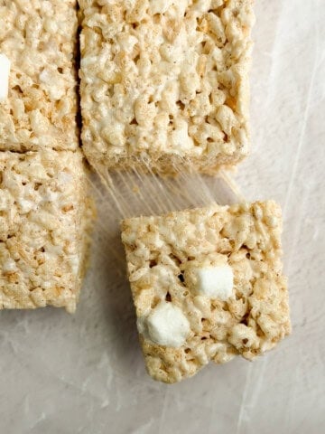 a close up of brown butter rice krispie treats with a marshmallow being pulled and stretched.