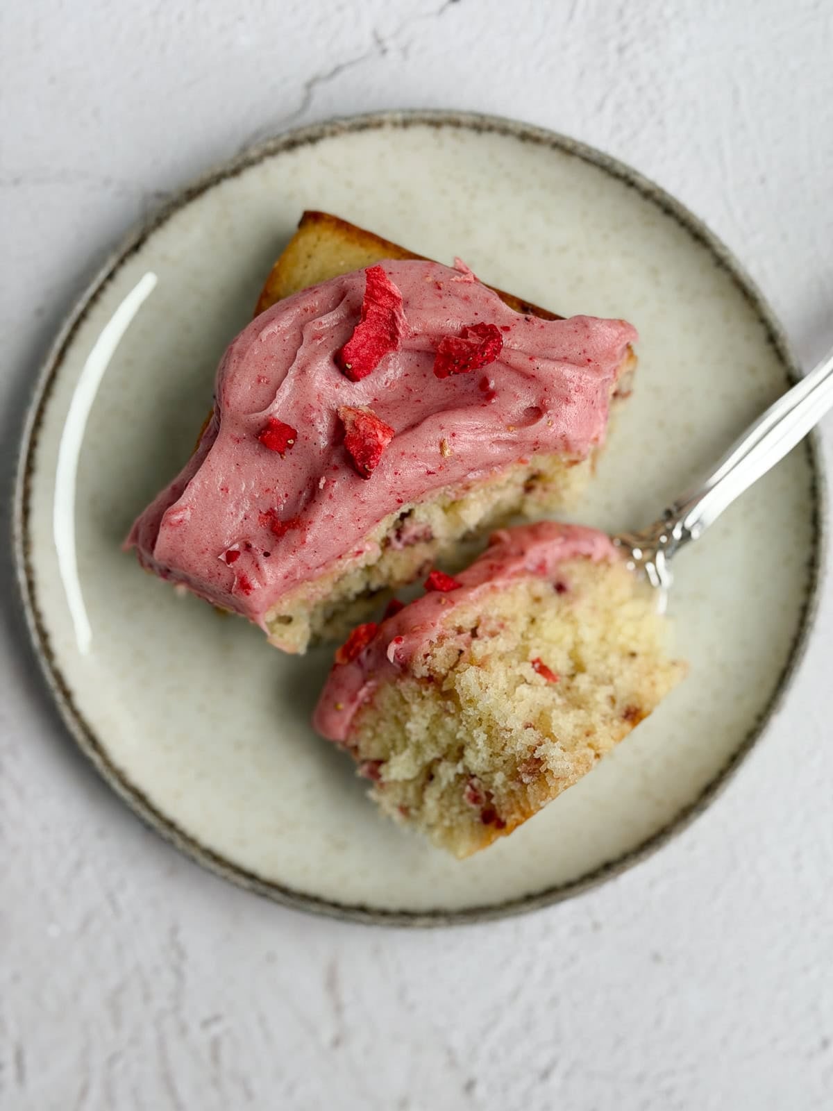 a single piece of the strawberry snack cake on a plate with a bite on a fork.