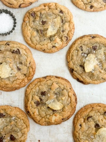 a bunch of chocolate chip potato chip cookies with a little salt on the side.
